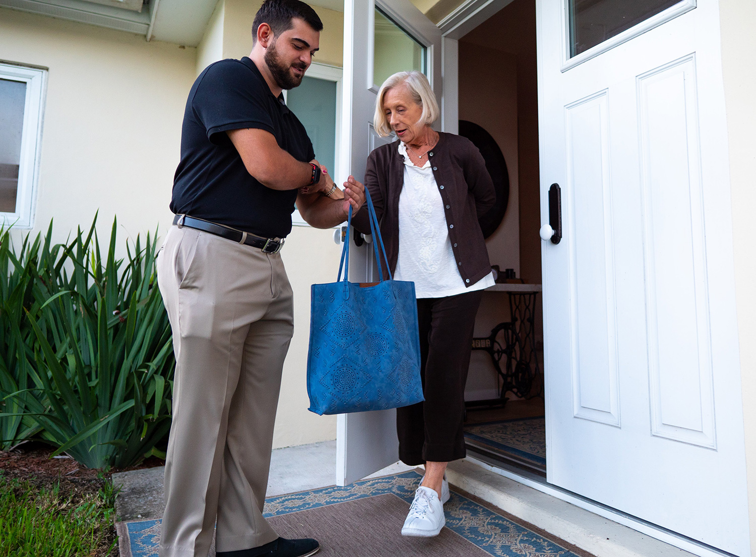 man helping senior woman to car -- door to door service